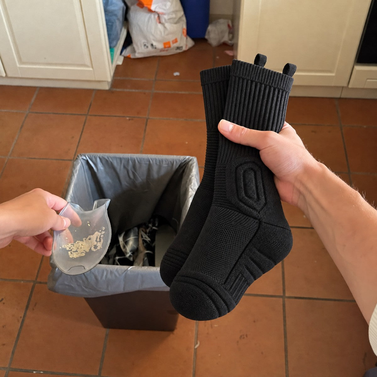 Trabajador tirando una plantilla de gel gastada mientras sostiene calcetines Talón Firme